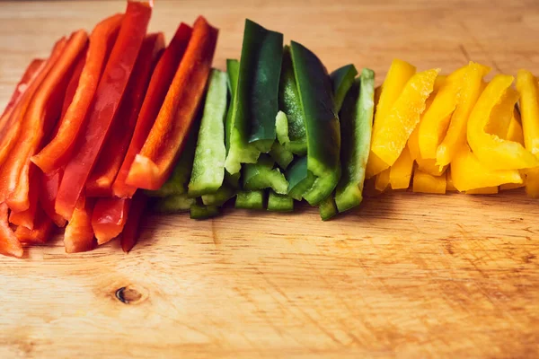 Kırmızı biber, yeşil biber ve ahşap masada sarı biber.