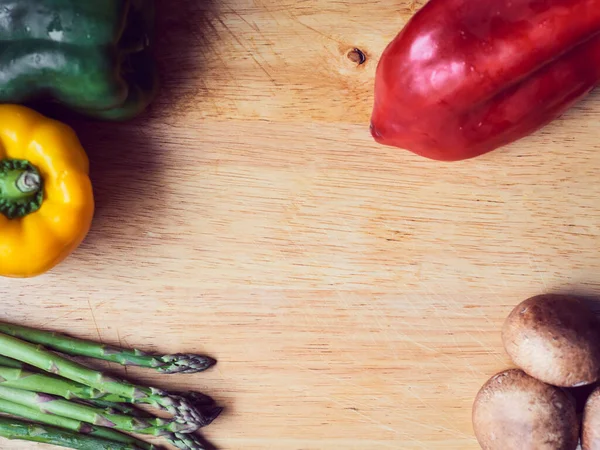 Kırmızı biber, yeşil biber ve ahşap masada sarı biber.