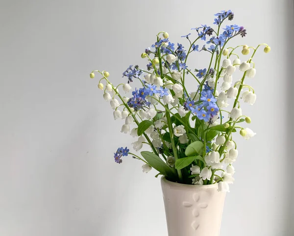 Spring bouquet of lilies of the valley and blue flowers on a white background. Spring flowers. A gift to your loved ones.