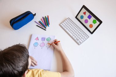 Öğrenci çocuk akademik görevlerini yapıyor ve internet bağlantısıyla evden öğreniyor. Online eğitim. Sosyal uzaklık kavramı. Üst görünüm.