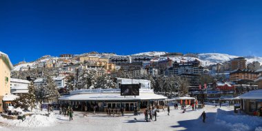 Panoramic view of the main square of Pradollano in Sierra Nevada, Granada. A sunny day after a heavy snowfall in winter. clipart
