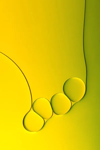 Macro photography of small drops of oil floating on water with yellow background. Abstract composition of great beauty. Background for design.