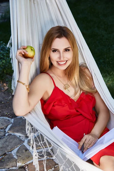 Beautiful woman model with long blond hair lies in a hammock rel — Stock Photo, Image