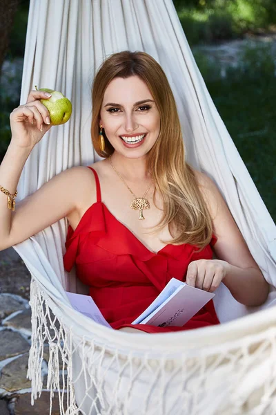 Beautiful woman model with long blond hair lies in a hammock rel — Stock Photo, Image