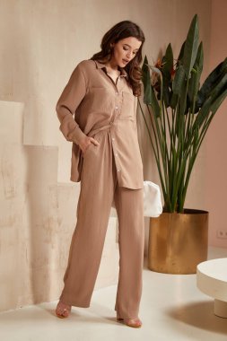 Güzel esmer kadın doğal makyaj kıyafetleri giyer günlük kıyafet ofis tarzı kıyafet giyer tamamen bej bluz ve pantolon takım elbise, romantik randevu işi çanta iç merdiven saksısı.