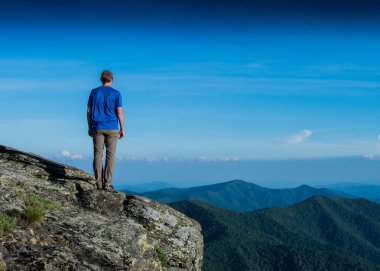Male Hiker Stands Over Ridge Line clipart