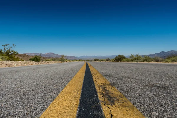 Vue du niveau de la route des rayures à travers le désert — Photo