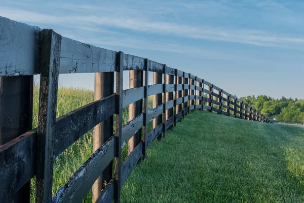Travnatém kopci snížit o černé plotu — Stock fotografie