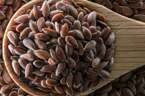 Colher de madeira cheia de sementes de linho marrom — Fotografia de Stock