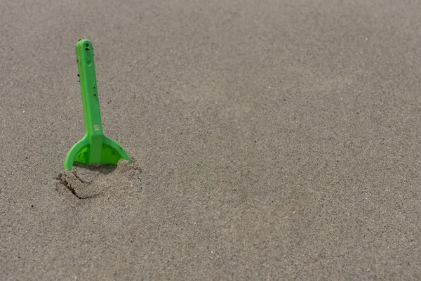 Брудні зелений лопатою покопавшись в вологий пісок — стокове фото