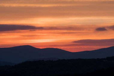 Parlak turuncu bulutlu gökyüzü dağ sırtlar yukarıda
