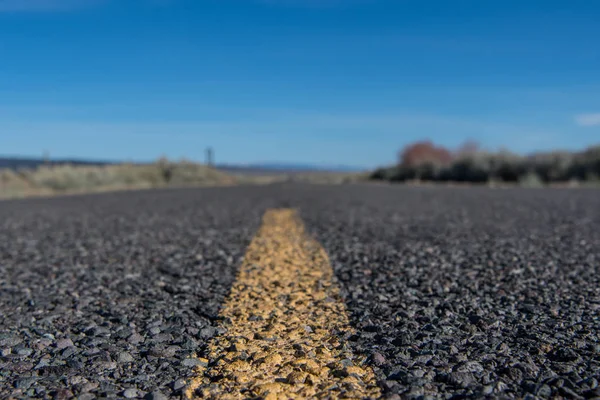 Vista de ângulo baixo da faixa amarela na estrada do deserto áspero — Fotografia de Stock