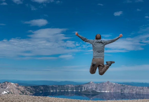Hombre salta en vista al lago del cráter — Foto de Stock