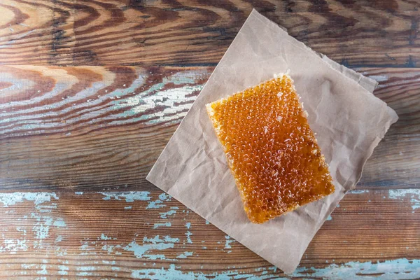 Méz fésű és a barna papír a régi asztallap — Stock Fotó