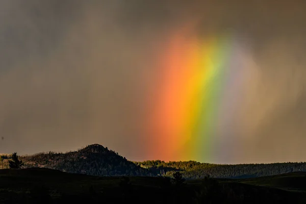 Amplio arco iris brilla a través de espesa nube de tormenta — Foto de Stock