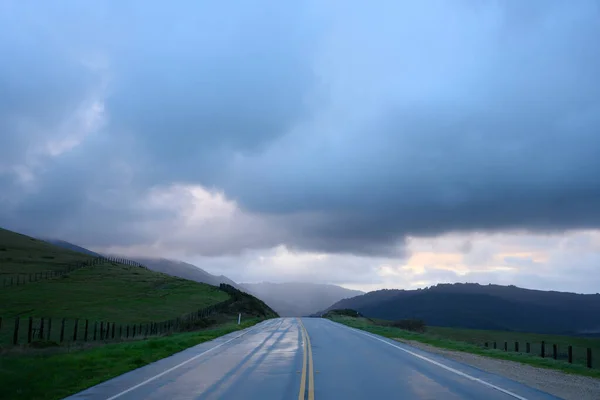Cesta míří do velkých kopců pod deštivými mraky — Stock fotografie