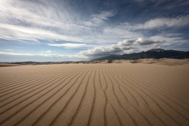 Kum tepelerinin ve dağların üzerindeki bulutlu gökyüzü