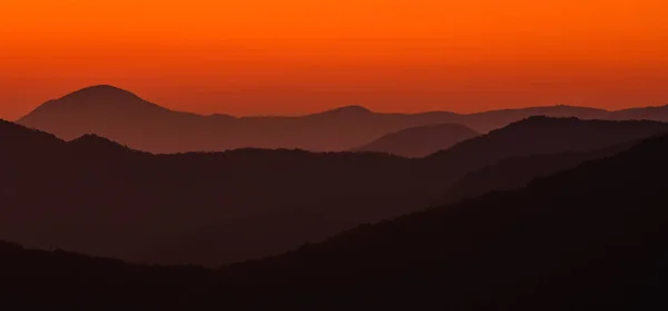 Dunst trennt Schichten oranger Berge — Stockfoto