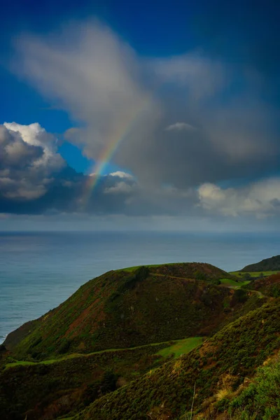 Arco iris a través de nubes sobre la costa del Pacífico — Foto de Stock