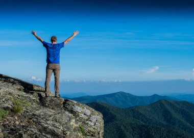 Dağ Tazeliğini hisset Bir adam vadiye bakarken kollarını uzatıyor