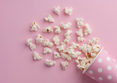 Pembe arka planda patlamış mısır, sinema, sinema ve eğlence konsepti