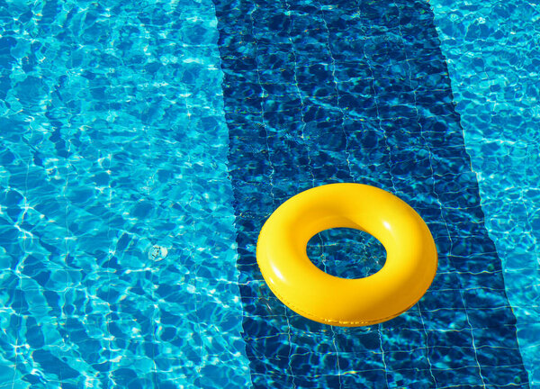 Yellow pool float, ring floating in a refreshing blue swimming pool