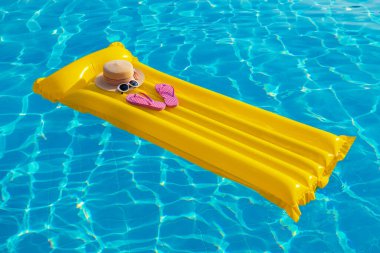 Yaz tatili geçmişi. Şişme şişme yatak, parmak arası terlik ve yüzme havuzunda şapka..