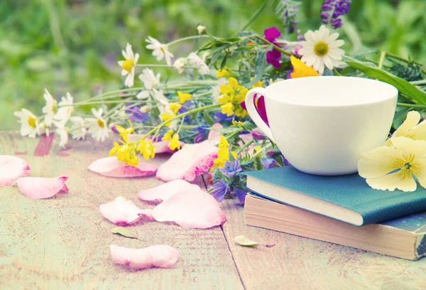 Books, flowers and white cup on wooden table