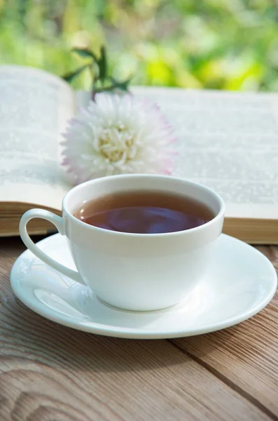 Books, flowers and white cup on wooden table