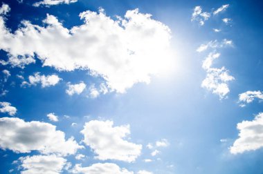 Mavi gökyüzünde beyaz bulutlar ve güneş