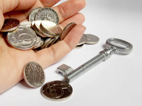 Zilveren munten in de hand met sleutel in achtergrond — Stockfoto