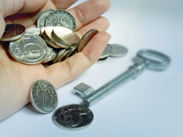 Zilveren munten in de hand met sleutel in achtergrond — Stockfoto