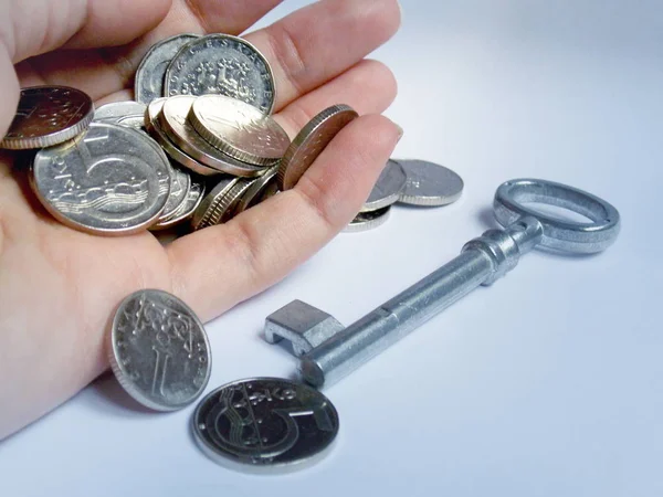 Zilveren munten in de hand met sleutel in achtergrond — Stockfoto