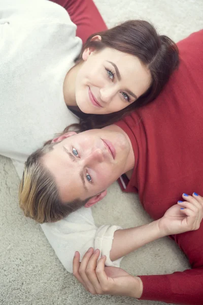 Par liggande på golvet och ler mot kameran — Stockfoto