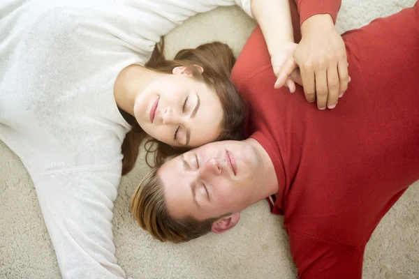 Joven pareja durmiendo en blanco alfombra — Foto de Stock