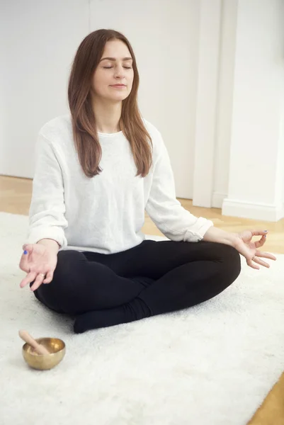 Mujer joven sentada en la alfombra y meditando —  Fotos de Stock