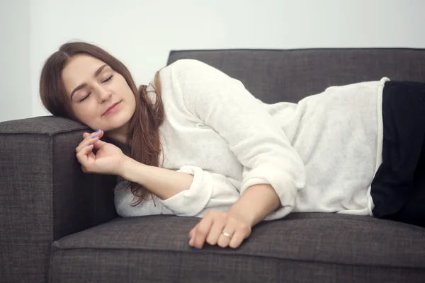 Joven mujer acostada en el sofá y está durmiendo — Foto de Stock
