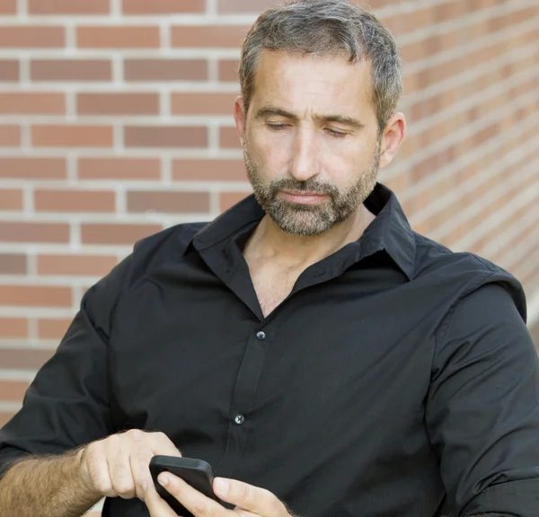 Retrato de homem bonito mensagens de texto em seu telefone — Fotografia de Stock