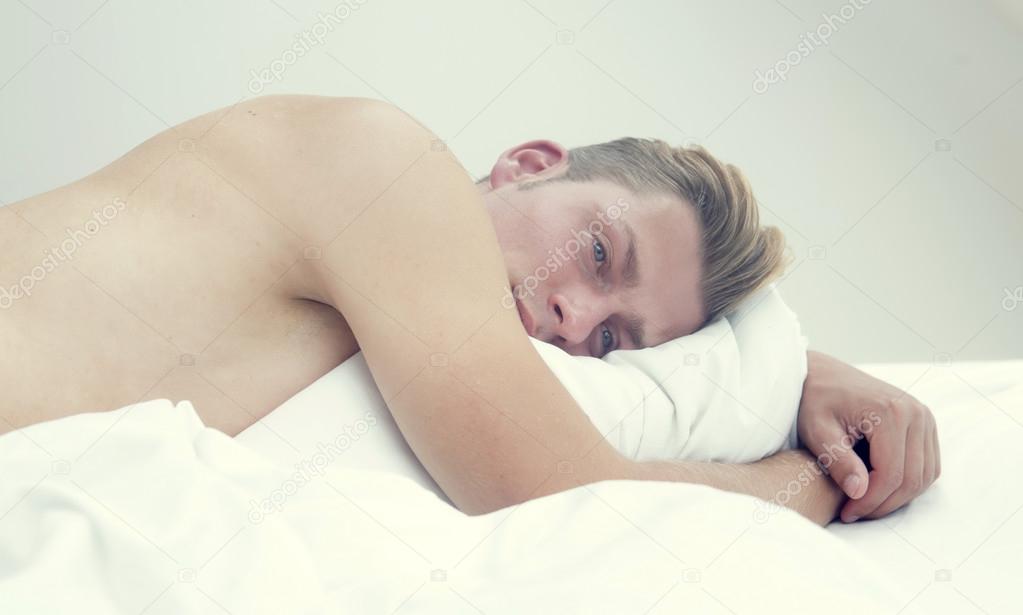 portrait of handsome man lying in bed