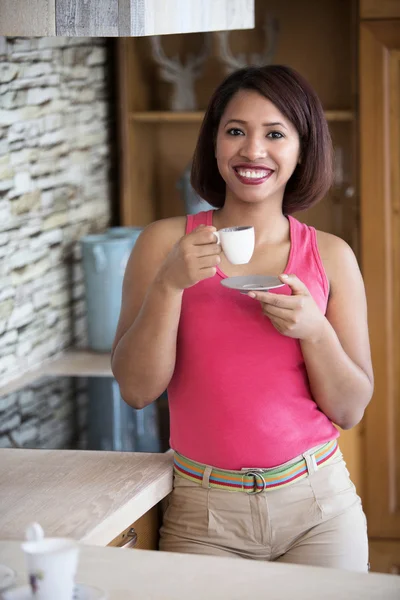 Junge Frau steht in Küche und trinkt Kaffee — Stockfoto