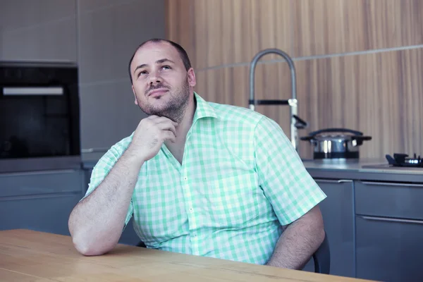 Übergewichtiger Mann sitzt am Küchentisch — Stockfoto