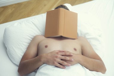 kitap onun yüzünde ile yatakta uyuyan adam