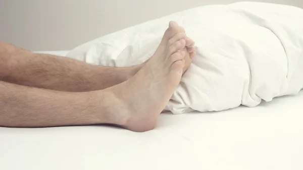 Primer plano de las piernas peludas y los pies del hombre en la cama — Foto de Stock