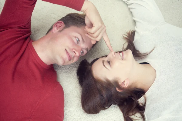 Retrato de pareja joven siendo divertido acostado en la alfombra —  Fotos de Stock