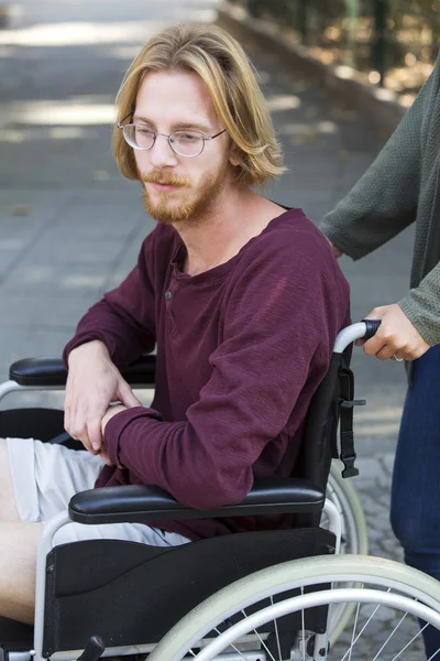 Młody człowiek w wózku inwalidzkim smutna — Zdjęcie stockowe