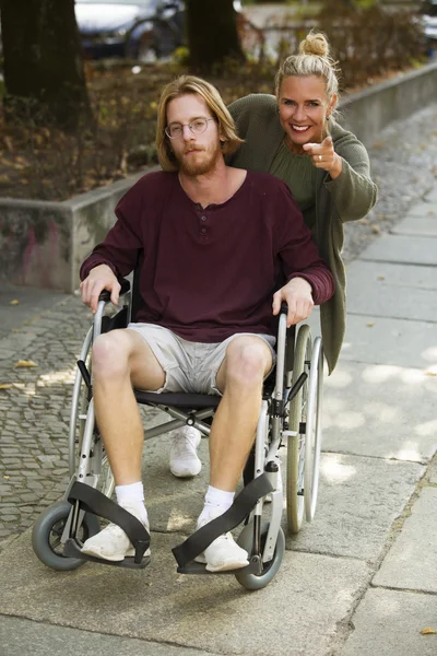 Hombre en silla de ruedas y mujer mostrándole algo — Foto de Stock