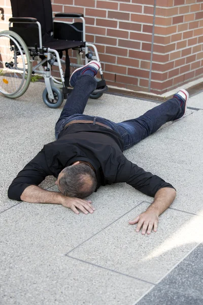 Mann liegt auf Gehweg neben Rollstuhl — Stockfoto