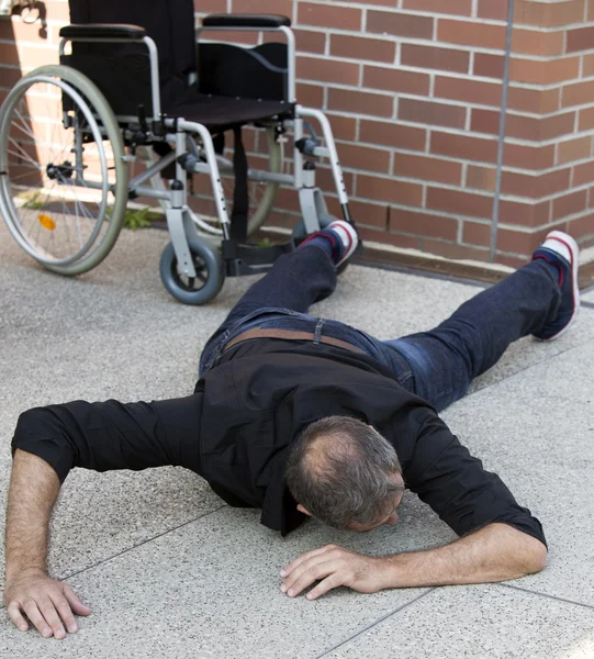 Gehbehinderter Mann nach Sturz aus Rollstuhl am Boden — Stockfoto