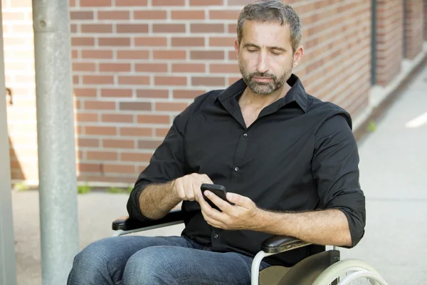 Człowiek w wózku SMS-y na swój telefon — Zdjęcie stockowe