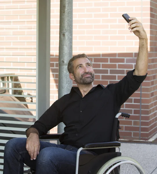 Człowiek na wózku inwalidzkim, biorąc selfie — Zdjęcie stockowe